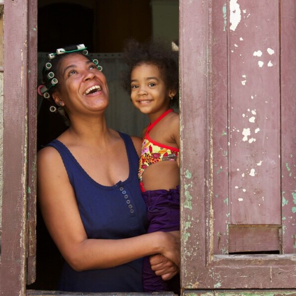 Kuba, Frau mit Kind auf dem Arm steht am Fenster, Latin America Tours, Reisen